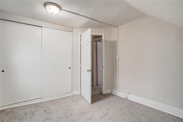 unfurnished bedroom with light carpet, vaulted ceiling, and a closet