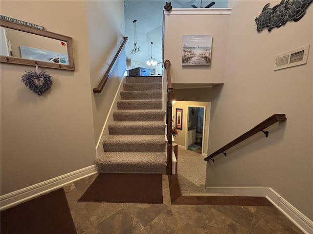 staircase with a towering ceiling and a chandelier