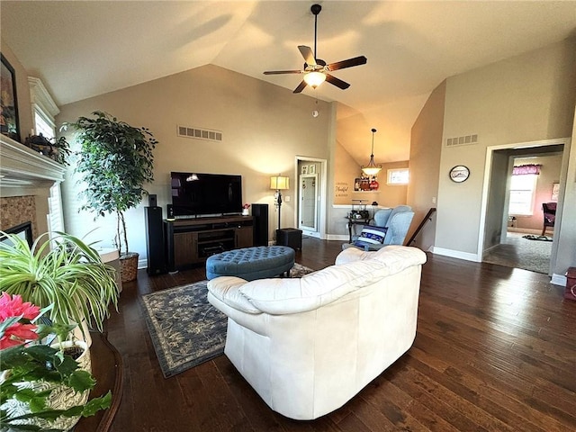 living room featuring ceiling fan, lofted ceiling, dark wood-type flooring, and a tile fireplace