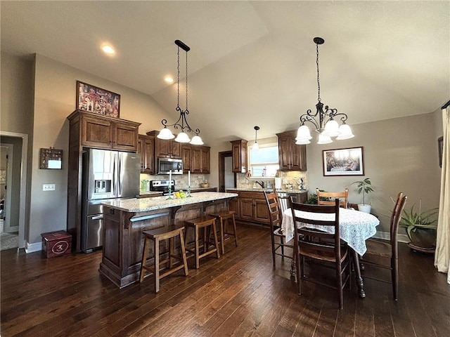 kitchen with backsplash, stainless steel appliances, pendant lighting, a chandelier, and a center island