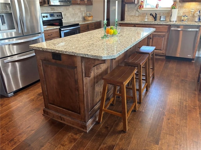 kitchen with a center island, sink, stainless steel appliances, dark hardwood / wood-style floors, and backsplash