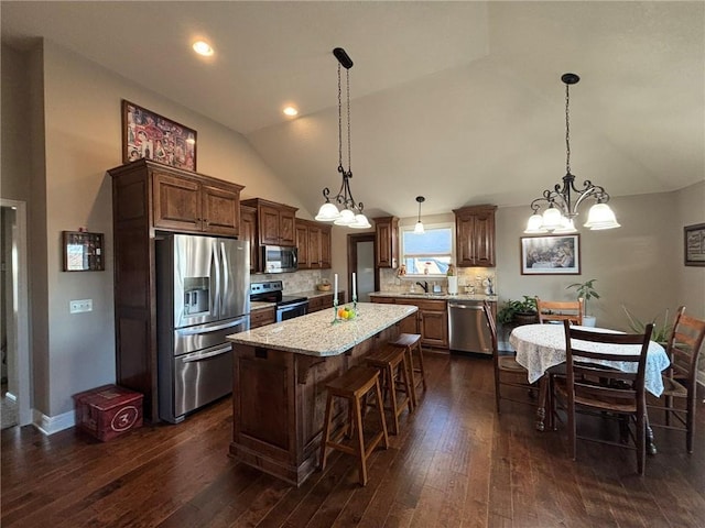 kitchen with a center island, lofted ceiling, backsplash, hanging light fixtures, and stainless steel appliances