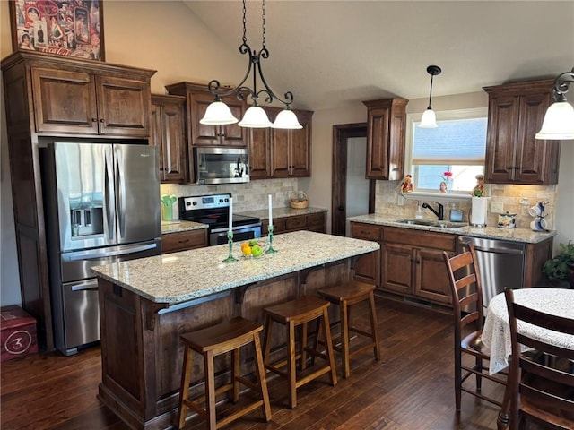 kitchen with sink, pendant lighting, decorative backsplash, a kitchen island, and appliances with stainless steel finishes