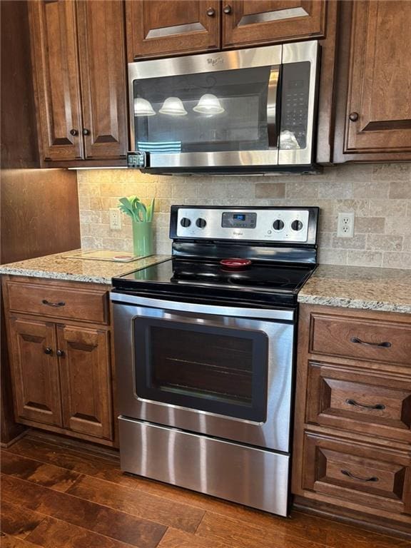 kitchen with stainless steel appliances, light stone counters, tasteful backsplash, and dark hardwood / wood-style floors