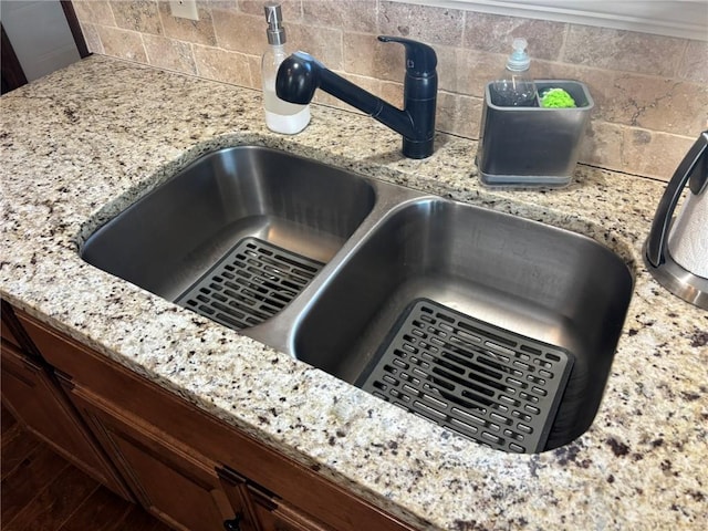 details with decorative backsplash, light stone countertops, and sink