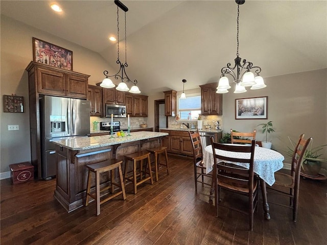 kitchen with a center island, hanging light fixtures, decorative backsplash, appliances with stainless steel finishes, and a chandelier