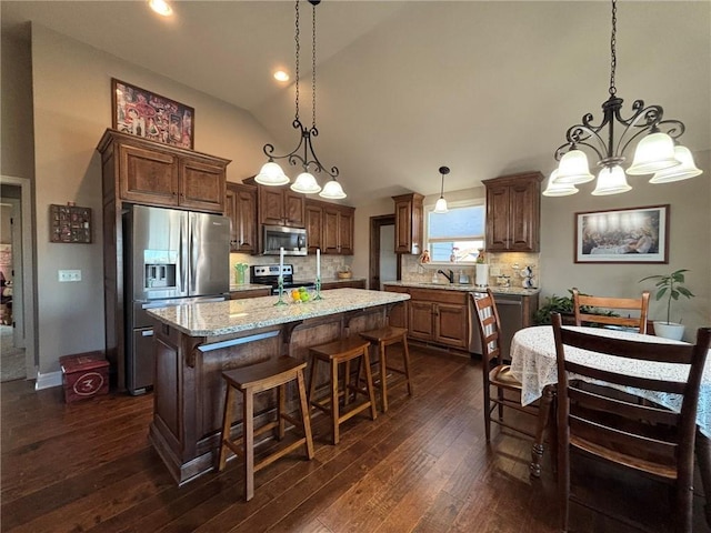 kitchen featuring a center island, hanging light fixtures, backsplash, a chandelier, and appliances with stainless steel finishes