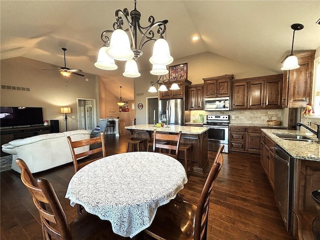 dining room with ceiling fan with notable chandelier, dark hardwood / wood-style floors, high vaulted ceiling, and sink