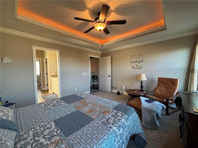 carpeted bedroom with ensuite bathroom, a raised ceiling, ceiling fan, and ornamental molding