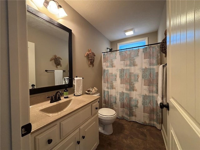 bathroom with a textured ceiling, vanity, toilet, and walk in shower