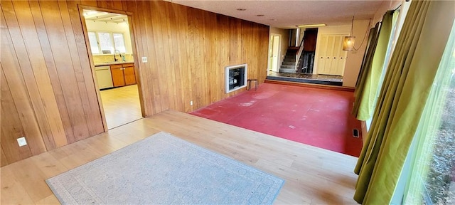 empty room with sink, wooden walls, and light wood-type flooring