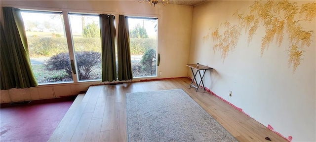 empty room with an inviting chandelier and light hardwood / wood-style flooring