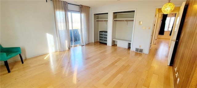 unfurnished bedroom featuring light wood-type flooring and two closets