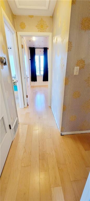 hallway with a raised ceiling and light hardwood / wood-style flooring