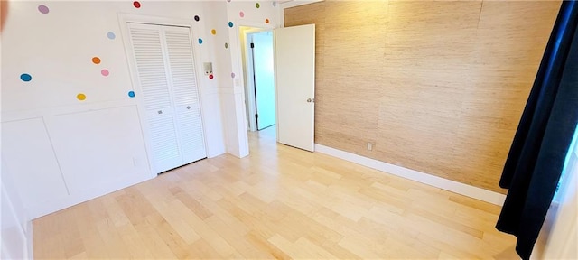 unfurnished bedroom with light wood-type flooring and a closet