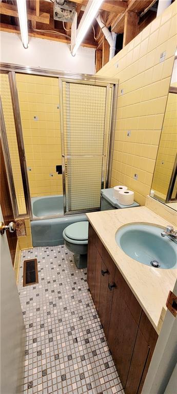 full bathroom featuring toilet, bath / shower combo with glass door, and vanity