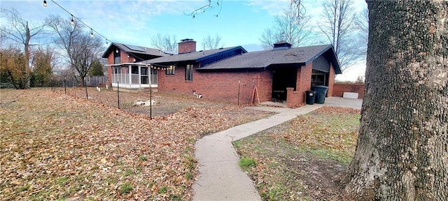 view of side of home featuring a sunroom and solar panels