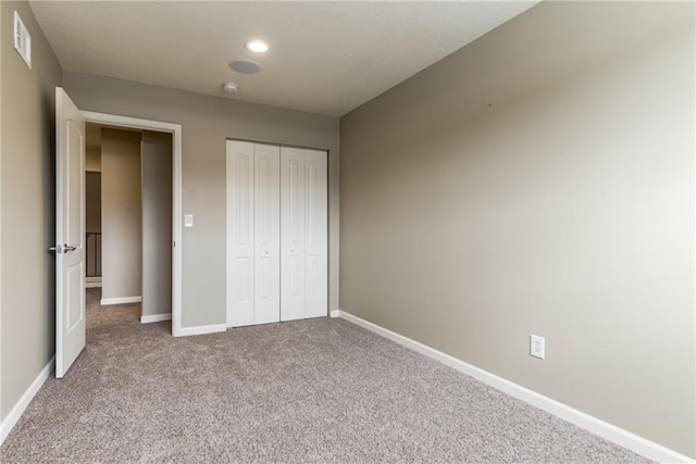 unfurnished bedroom featuring light carpet and a closet