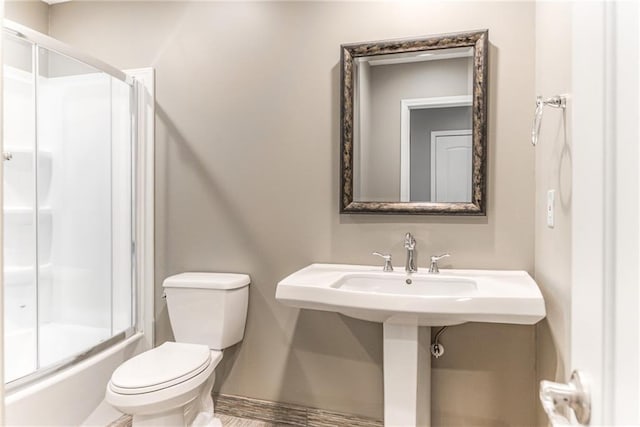 bathroom featuring combined bath / shower with glass door and toilet