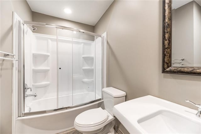 full bathroom featuring sink, bath / shower combo with glass door, and toilet