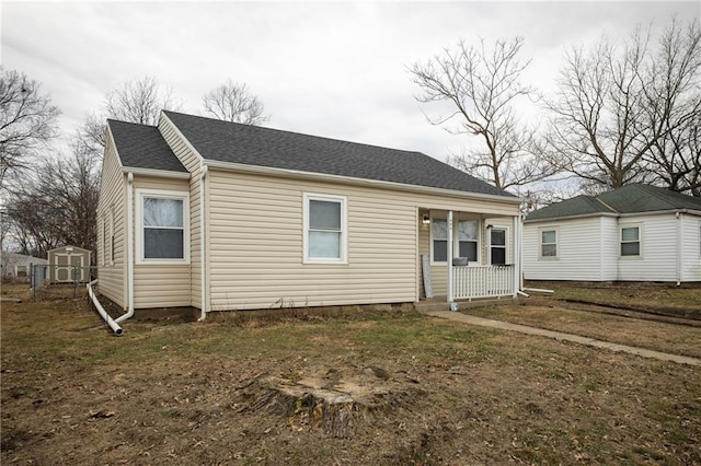 rear view of house with a porch, a lawn, and a shed