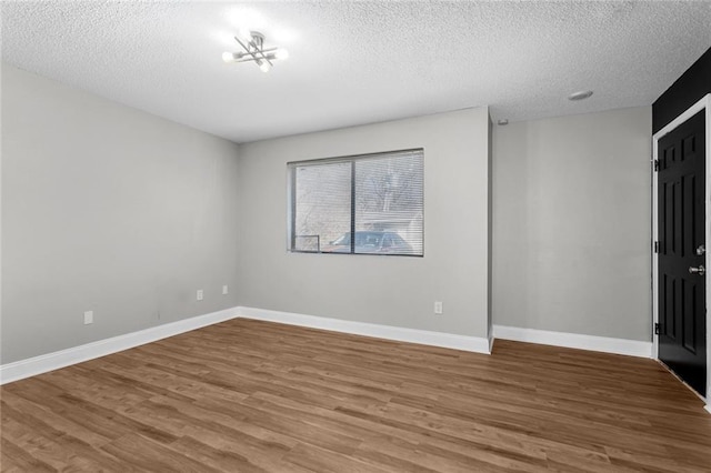 spare room with a chandelier, wood-type flooring, and a textured ceiling