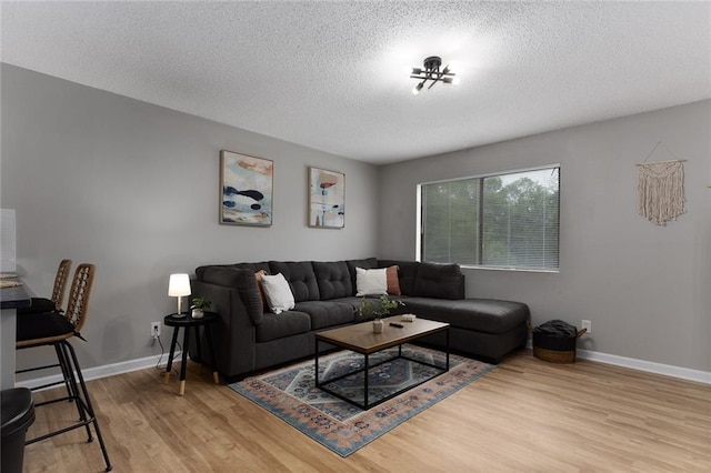 living room featuring light wood-type flooring and a textured ceiling