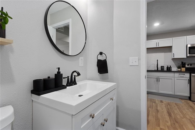 bathroom featuring decorative backsplash, wood-type flooring, vanity, and toilet