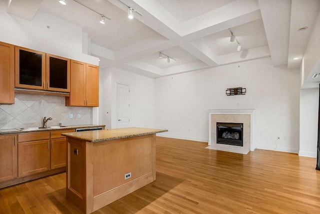 kitchen with a center island, light stone counters, light hardwood / wood-style flooring, and sink