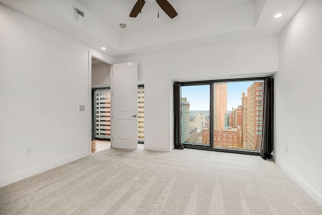 carpeted spare room featuring ceiling fan and a tray ceiling