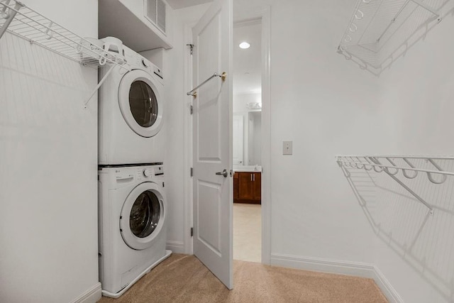 clothes washing area featuring carpet flooring and stacked washer / drying machine