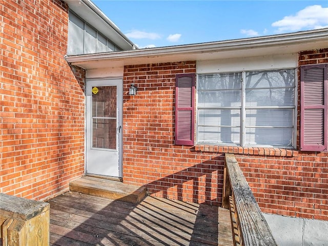 property entrance featuring board and batten siding and brick siding