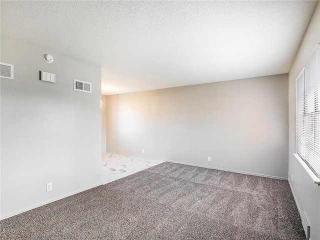 unfurnished room featuring carpet and a textured ceiling