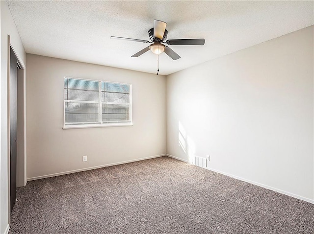 spare room featuring ceiling fan, carpet, and a textured ceiling