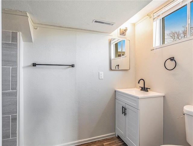 bathroom featuring hardwood / wood-style floors, vanity, a textured ceiling, and toilet