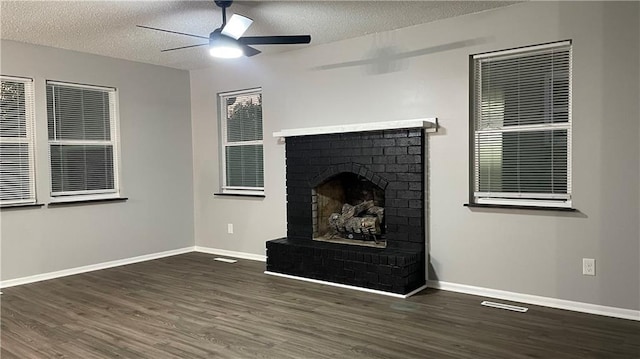 unfurnished living room featuring ceiling fan, dark hardwood / wood-style floors, a textured ceiling, and a brick fireplace