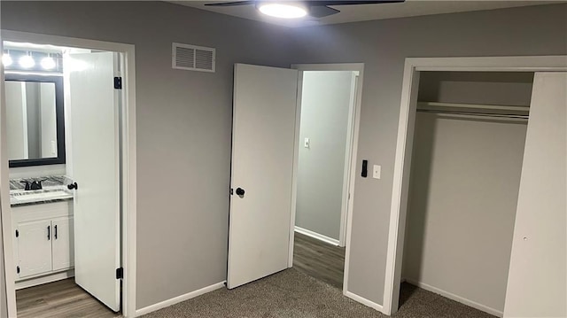 unfurnished bedroom with dark colored carpet, a closet, ceiling fan, and sink