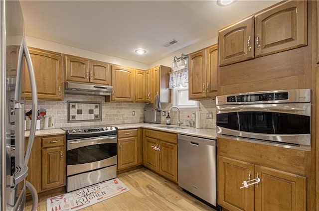 kitchen featuring decorative backsplash, sink, light hardwood / wood-style flooring, and appliances with stainless steel finishes