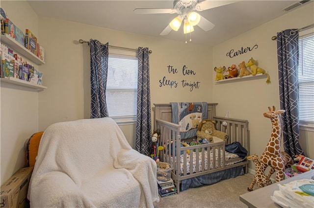 bedroom featuring ceiling fan, a crib, and carpet floors