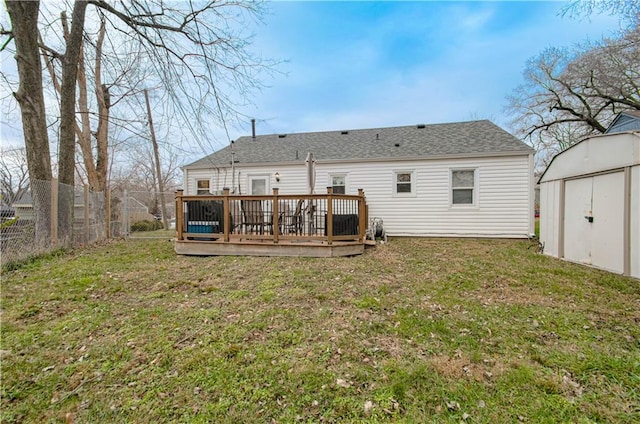 rear view of house with a yard, a deck, and a storage unit