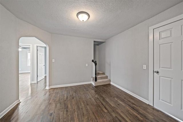 spare room with dark hardwood / wood-style floors, ceiling fan, and a textured ceiling