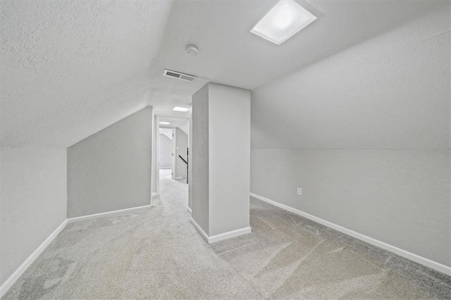 additional living space featuring carpet, lofted ceiling, and a textured ceiling