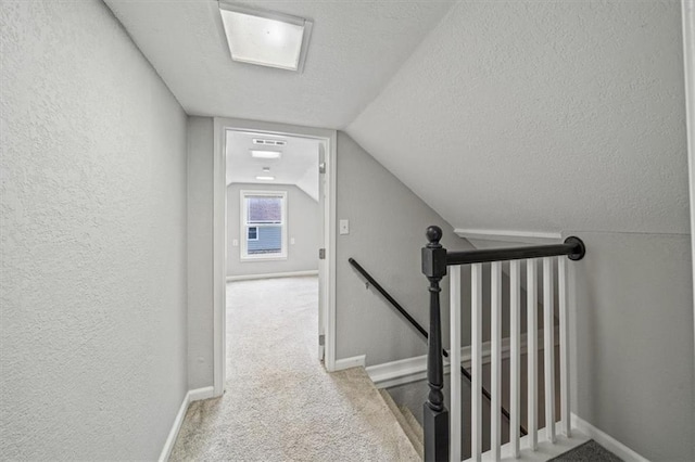 interior space featuring light colored carpet, lofted ceiling, and a textured ceiling