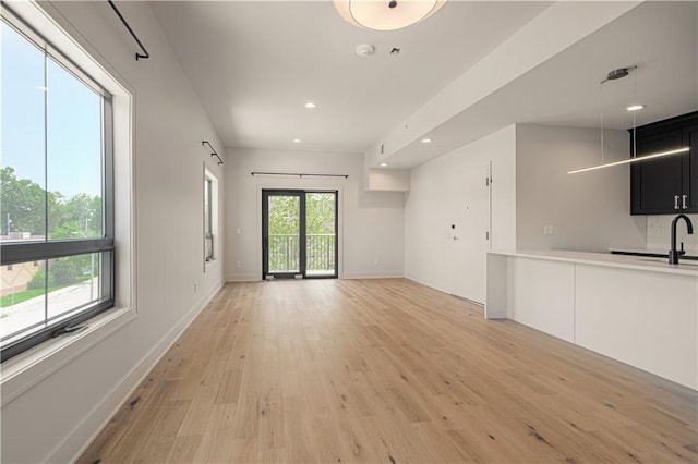 unfurnished living room featuring light hardwood / wood-style flooring, a wealth of natural light, and sink