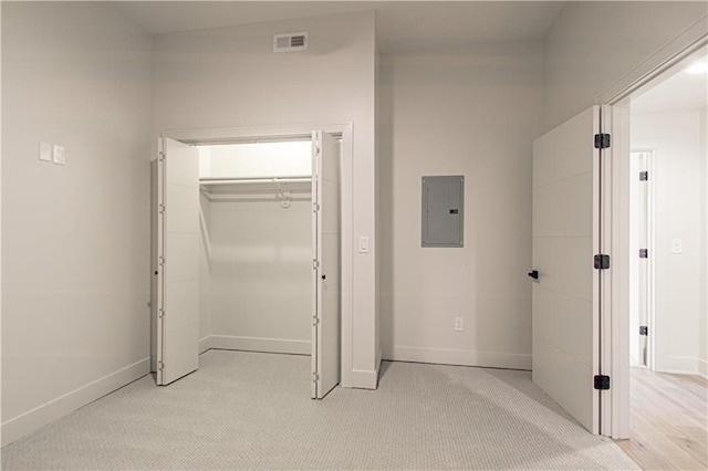 unfurnished bedroom featuring light colored carpet, electric panel, and a closet