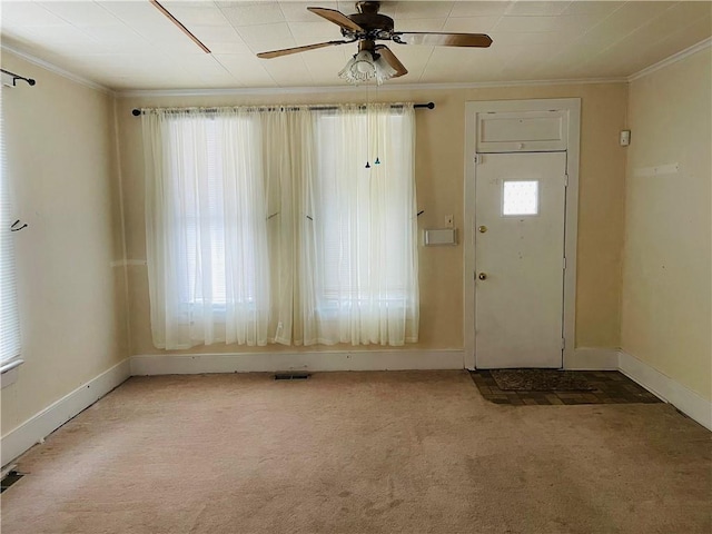 carpeted foyer featuring a wealth of natural light, ceiling fan, and ornamental molding