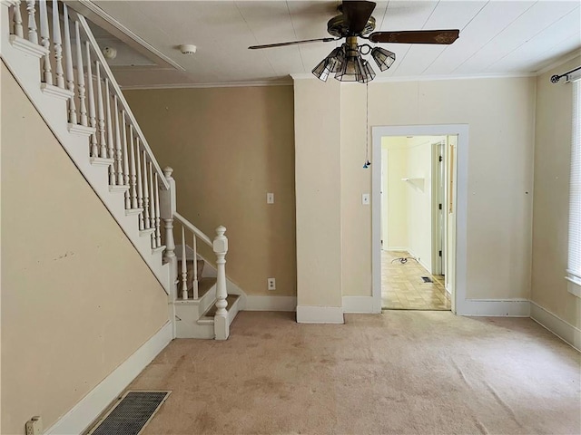 carpeted foyer entrance featuring ceiling fan and ornamental molding