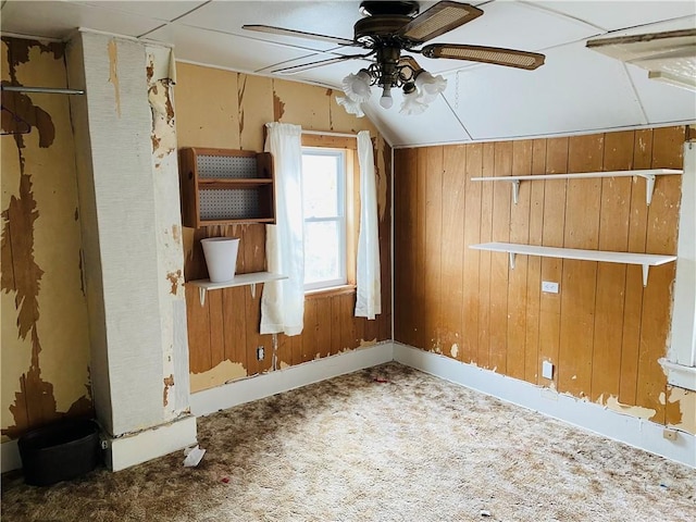 bonus room with carpet flooring, ceiling fan, wood walls, and lofted ceiling