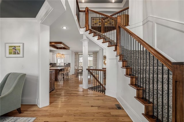 stairway with recessed lighting, wood finished floors, visible vents, baseboards, and crown molding