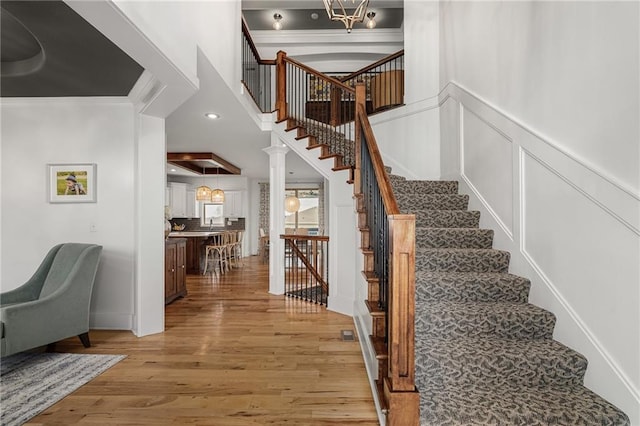 stairway with a wainscoted wall, crown molding, recessed lighting, a decorative wall, and wood finished floors